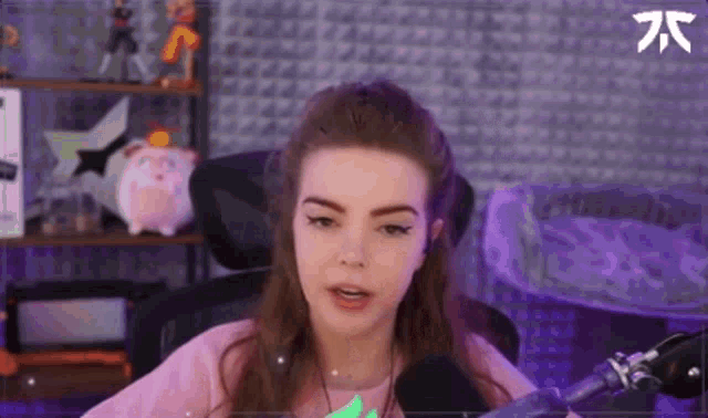 a woman is sitting in front of a microphone in a room with a piggy bank in the background .