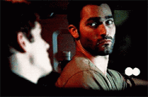 a man with a beard is looking at another man 's face .