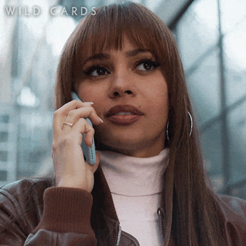 a woman is talking on a cell phone with the words wild cards visible behind her