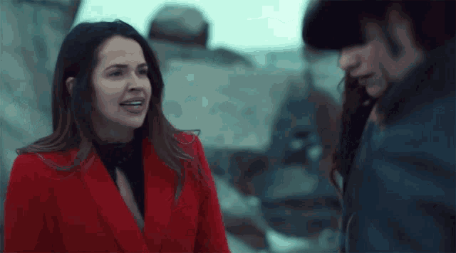 a woman in a red jacket is talking to another woman