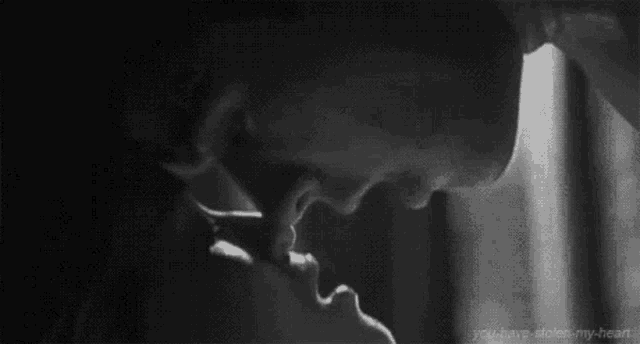 a black and white photo of a man and woman kissing each other .