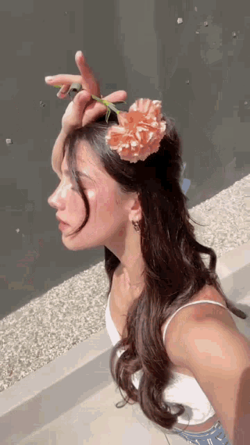 a woman is holding a flower in her hair .