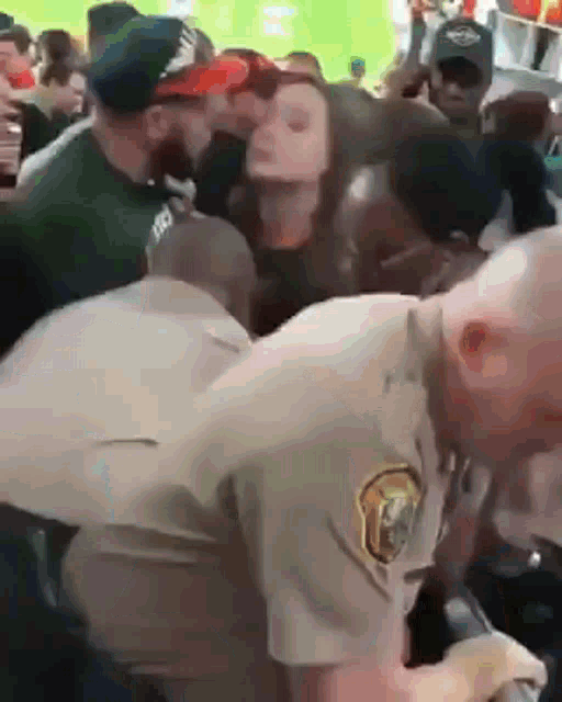 a police officer is standing in front of a crowd of people and talking into a microphone .