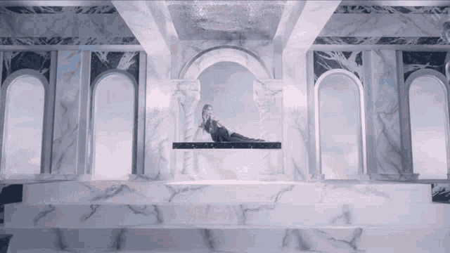 a woman in a black dress is laying on a marble throne