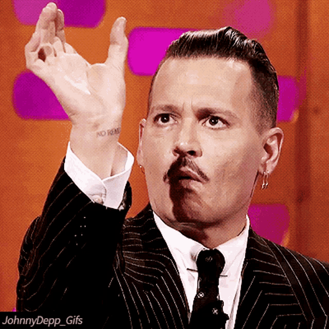 a man in a suit has a tattoo on his wrist that says " no him "