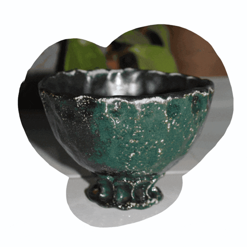a green and black bowl with a heart shaped frame around it