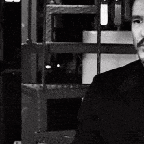 a man with a mustache is standing in front of a fence