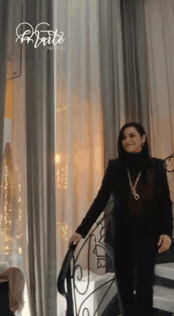 a woman in a black suit is standing on a set of stairs in front of a window .