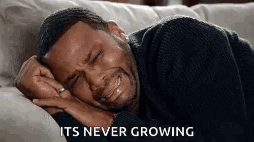 a man is crying while laying on a couch with his eyes closed .