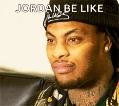 a man wearing a beanie and earrings is sitting on a couch and looking at the camera .
