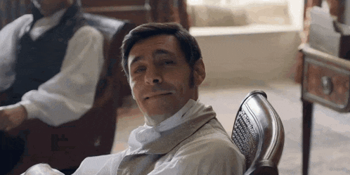 a man in a white shirt and tie is sitting in a chair .