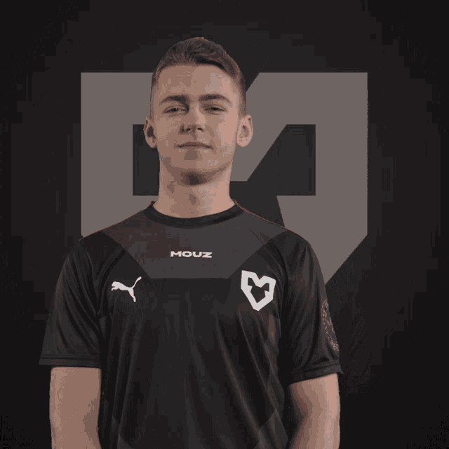 a young man wearing a black mouz jersey smiles with his eyes closed