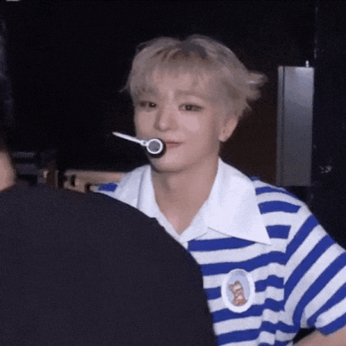 a young man wearing a blue and white striped shirt is talking to another person