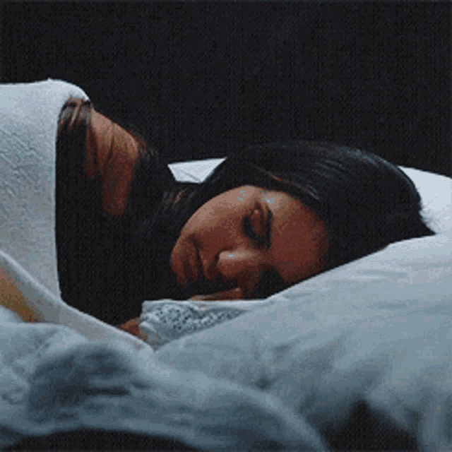 a woman is sleeping on a bed with her head on a pillow
