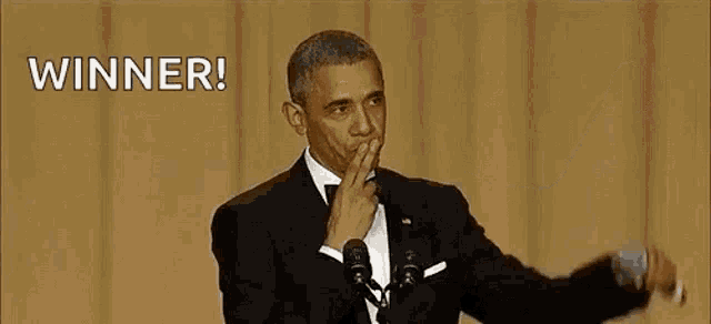 barack obama is giving a speech in front of a microphone while covering his mouth with his hand .