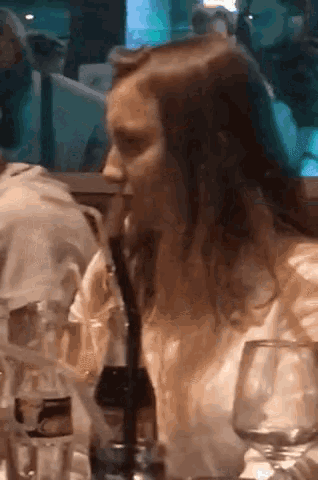 a woman sits at a table drinking from a bottle