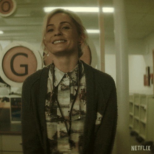 a woman smiles in front of a netflix sign