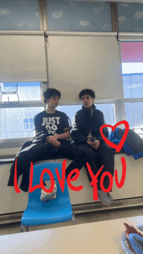 two boys sitting on a blue chair with i love you written on the wall
