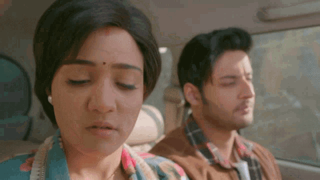 a man and a woman are in a car with their eyes closed