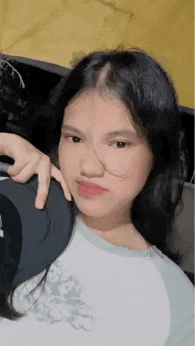 a young girl with long black hair is sitting in a car and taking a picture of herself .
