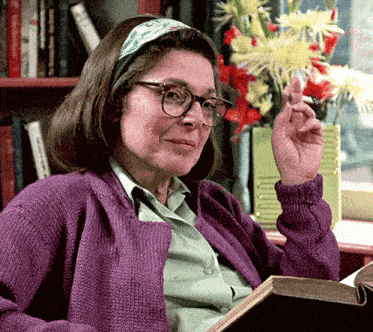 a woman in a purple sweater is reading a book