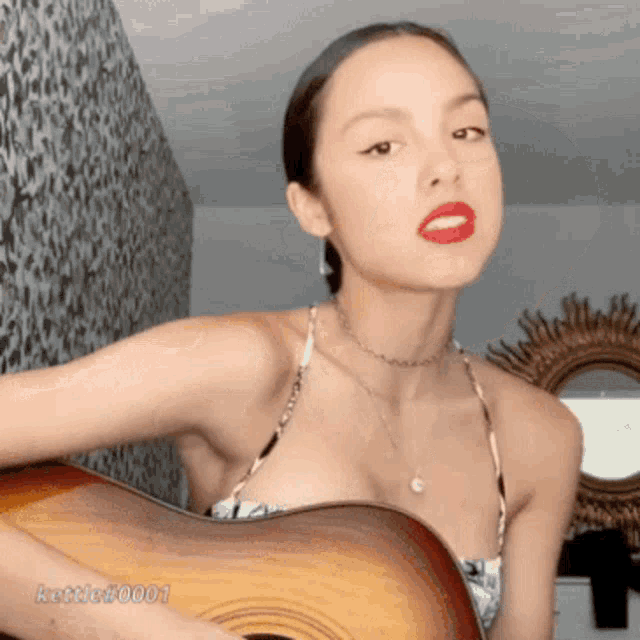 a woman in a bikini is holding a guitar with the name kettle0001 written on the bottom