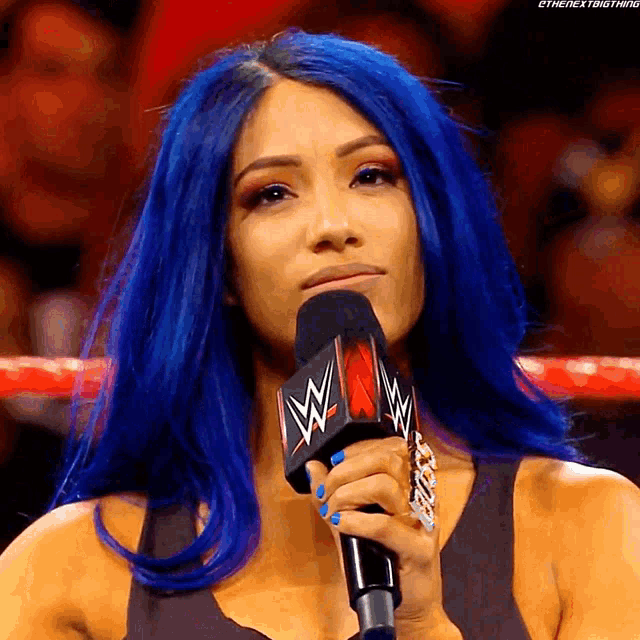 a woman with blue hair is holding a microphone that says wwe on it