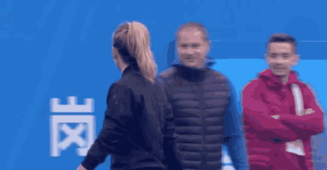 a woman in a ponytail is talking to a man in a red jacket .