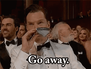 a man in a tuxedo is holding a martini glass in front of his face and says `` go away '' .