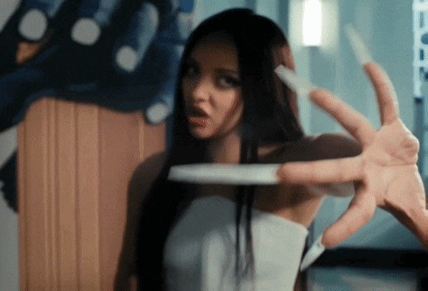 a woman in a white dress is holding a knife between her fingers .