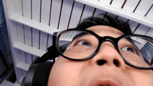 a man wearing glasses and headphones looks up at something