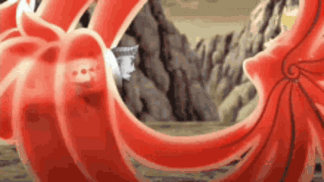 a close up of a red squid in a cartoon with a mountain in the background .
