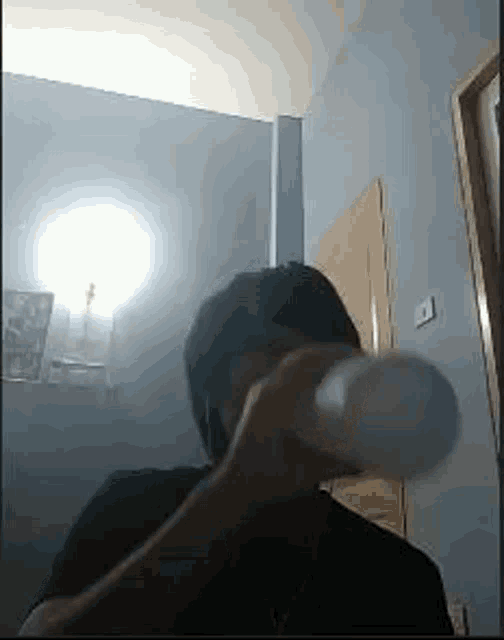 a man is drinking from a plastic bottle in a room .