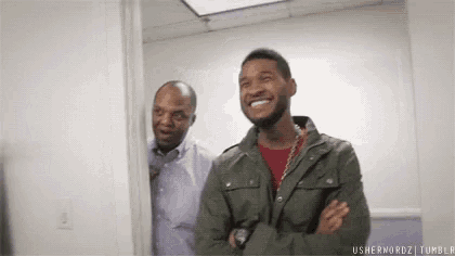a man in a green jacket is smiling while standing next to another man .