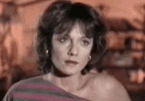 a woman is wearing a striped shirt and earrings and making a sad face .