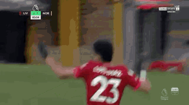 a soccer player wearing a red jersey with the number 23 on it is standing on a field .