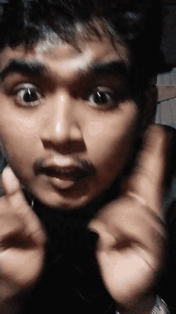 a close up of a man making a funny face with his hands