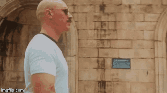 a bald man with a mustache is standing in front of a brick wall with the caption me leaving this post .