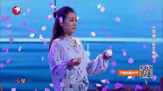 a woman in a polka dot shirt is standing in front of petals falling from the sky ..