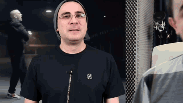a man wearing glasses and a black t-shirt with the letters sbm on the front