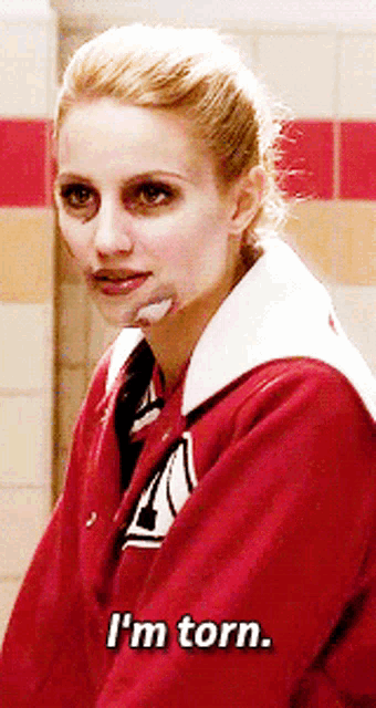 a woman in a red jacket says " i 'm torn " on the bottom
