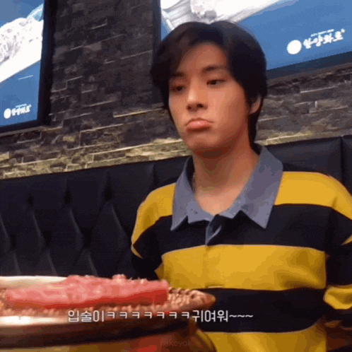 a man wearing a yellow and black striped shirt holds a plate of food
