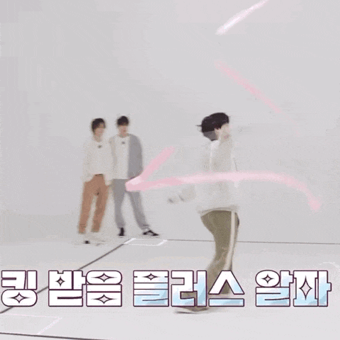 a man is playing with a pink ribbon in a room while two other men watch .