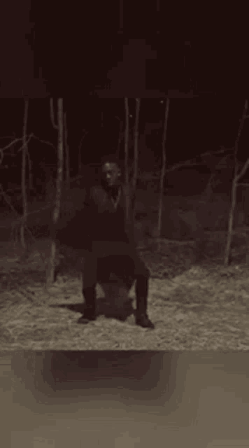 a man in a red coat is standing in a dark forest .