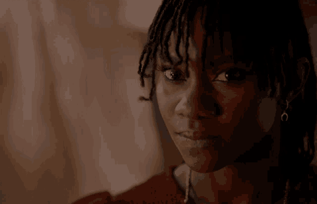 a close up of a woman 's face with dreadlocks and a red shirt