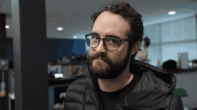a man with a beard wearing glasses and a jacket