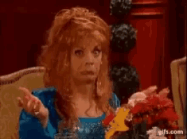 a woman with red hair is sitting on a couch with a glass of water and flowers .