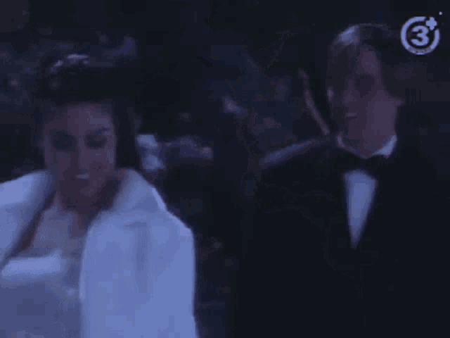 a man and a woman are standing next to each other in the dark .