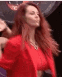 a woman in a red dress is dancing in front of a disco ball