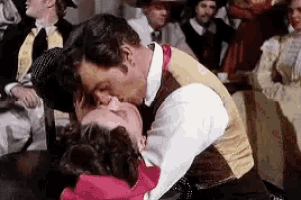 a man is kissing a woman in front of a crowd of people .